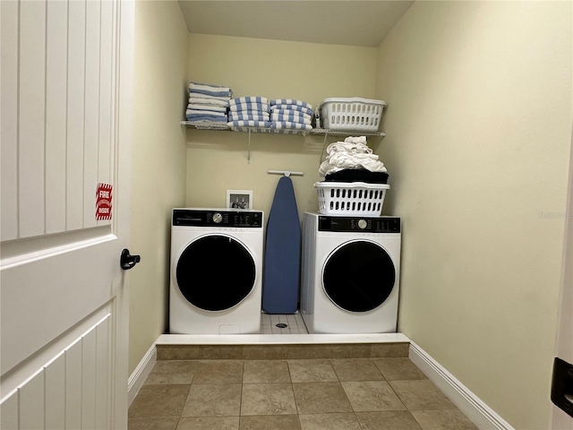 laundry area featuring tile patterned floors, laundry area, baseboards, and separate washer and dryer