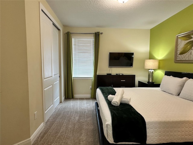 carpeted bedroom with a closet, baseboards, and a textured ceiling