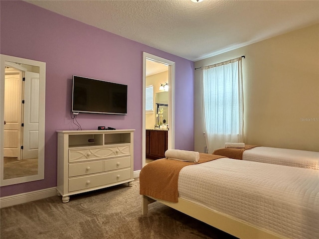 carpeted bedroom with ensuite bathroom, a textured ceiling, and baseboards