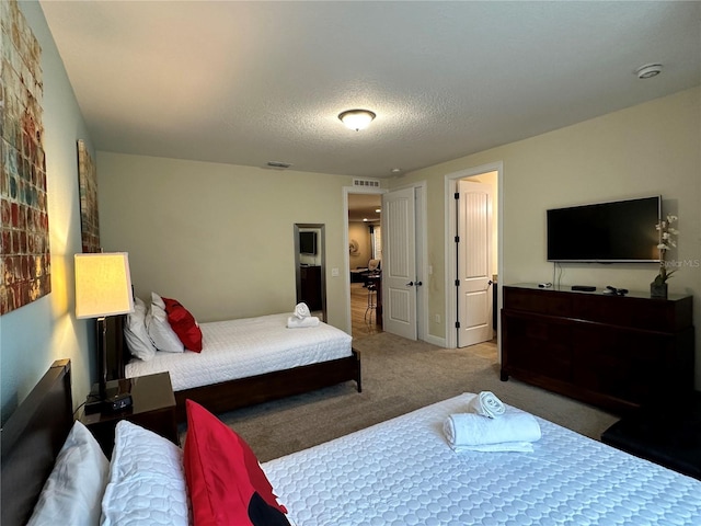 bedroom featuring carpet floors, visible vents, and a textured ceiling