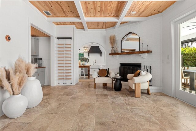 living room featuring wooden ceiling, a brick fireplace, visible vents, and coffered ceiling