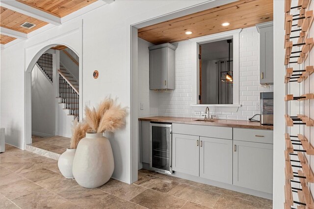 interior space featuring visible vents, wine cooler, tasteful backsplash, and wooden ceiling