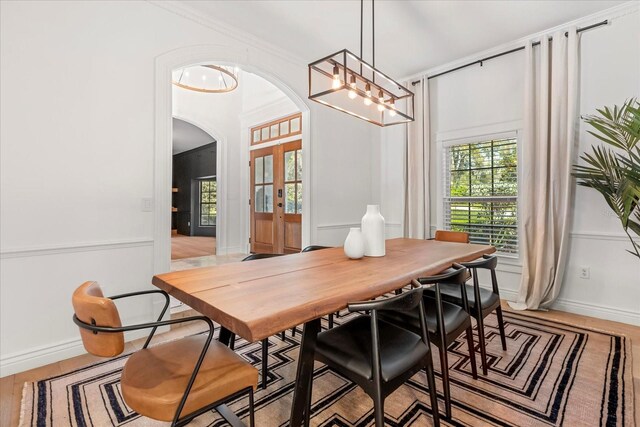 dining room featuring french doors, arched walkways, light wood-style floors, and baseboards