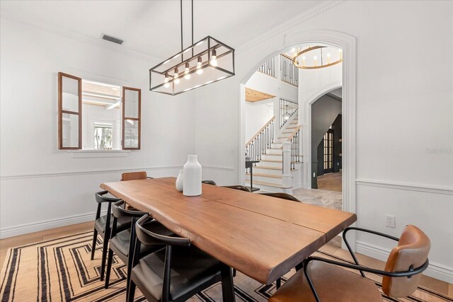 dining space with baseboards, visible vents, arched walkways, ornamental molding, and stairs