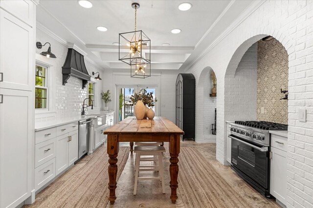 kitchen with brick wall, crown molding, light countertops, decorative backsplash, and appliances with stainless steel finishes