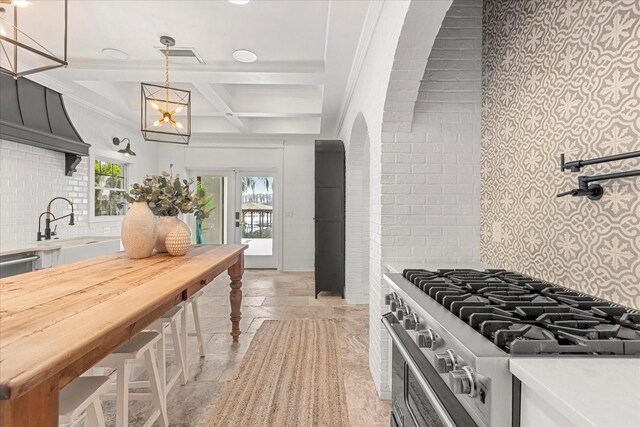 kitchen featuring beam ceiling, backsplash, coffered ceiling, stone tile floors, and light countertops