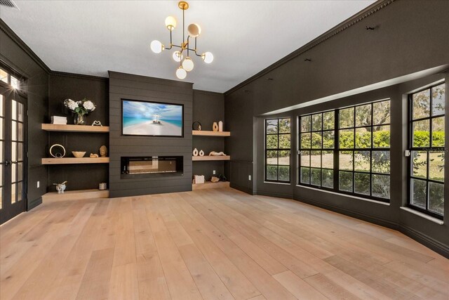 living room with built in shelves, a large fireplace, a chandelier, light wood-type flooring, and ornamental molding