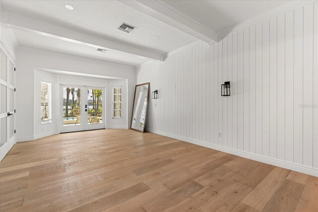 unfurnished room featuring visible vents, baseboards, light wood-type flooring, beam ceiling, and french doors