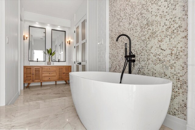 bathroom featuring double vanity, a soaking tub, and marble finish floor