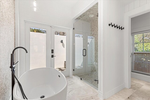 bathroom with a freestanding bath, marble finish floor, and a stall shower