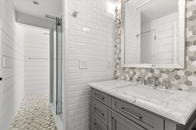 bathroom with decorative backsplash, tile walls, vanity, and a tile shower