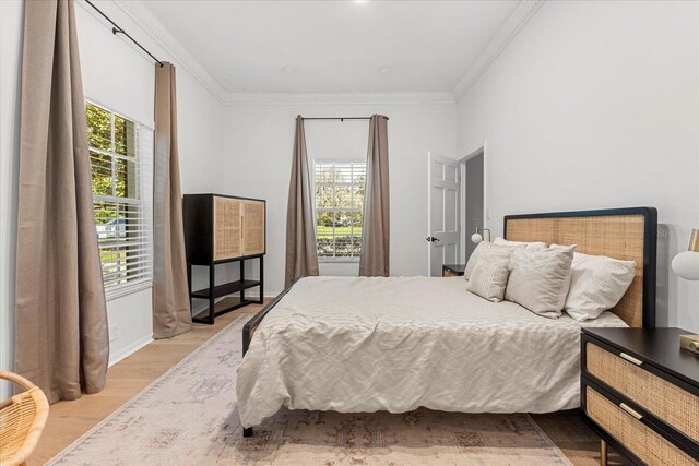 bedroom with wood finished floors and crown molding