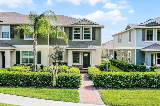 townhome / multi-family property with roof with shingles and stucco siding