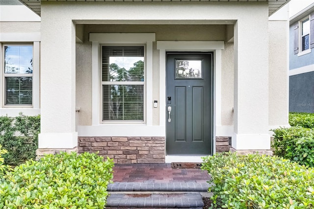 view of exterior entry with stone siding and stucco siding