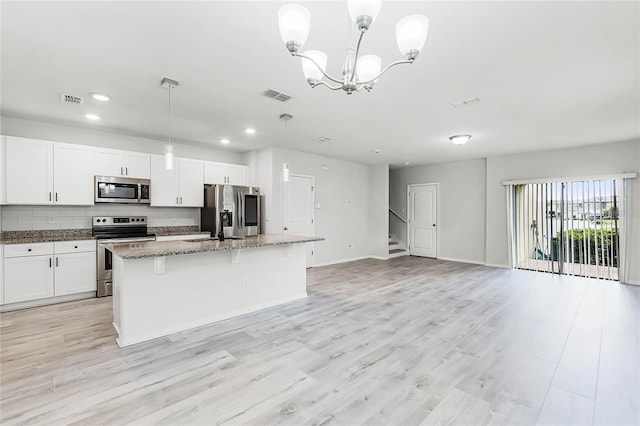 kitchen with dark stone counters, stainless steel appliances, visible vents, and a center island