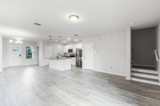 unfurnished living room featuring light wood finished floors, recessed lighting, visible vents, baseboards, and stairs