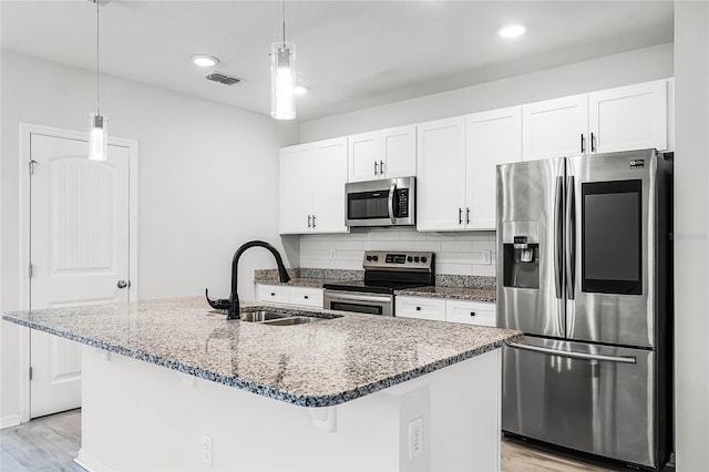 kitchen with light wood finished floors, white cabinets, decorative backsplash, appliances with stainless steel finishes, and a sink