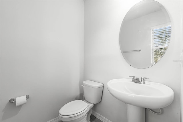 bathroom featuring baseboards, a sink, and toilet