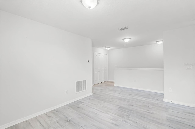 spare room featuring light wood-type flooring, baseboards, and visible vents