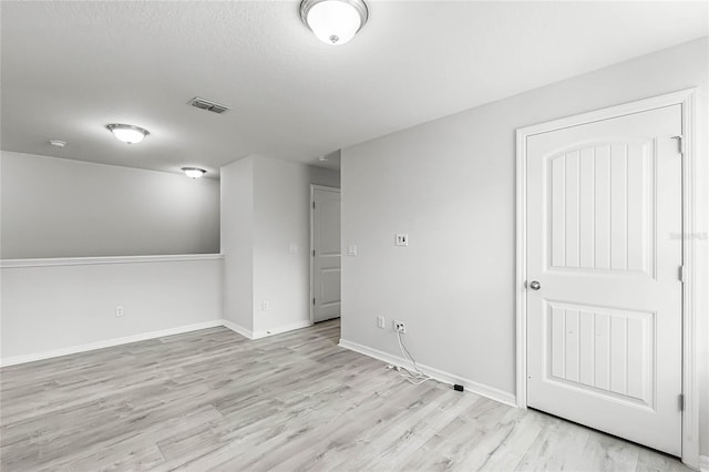 unfurnished room with light wood-style floors, baseboards, and visible vents