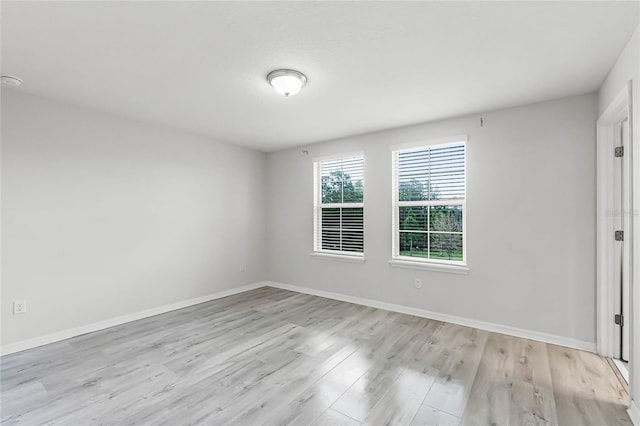 unfurnished room featuring baseboards and light wood finished floors