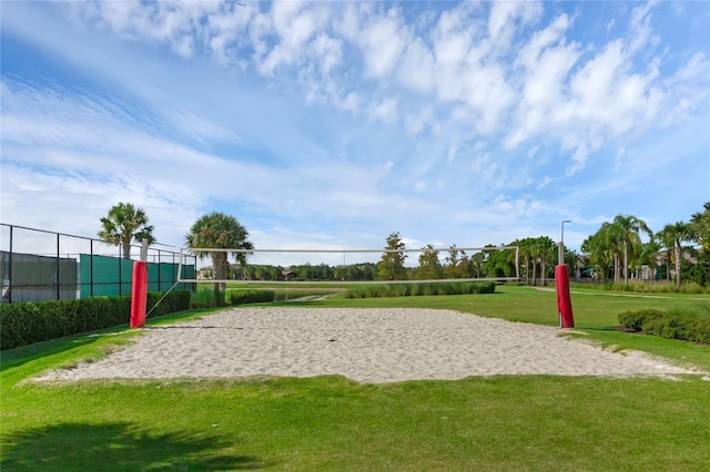 view of property's community featuring fence, volleyball court, and a lawn