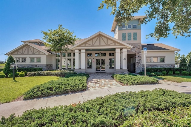 view of front of property with stone siding, french doors, and stucco siding