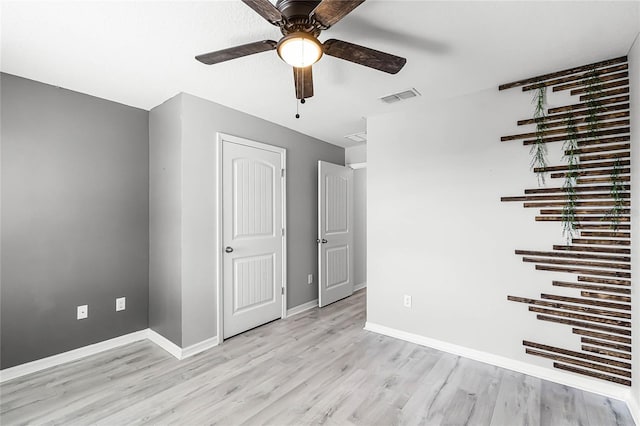 spare room with light wood-type flooring, visible vents, ceiling fan, and baseboards