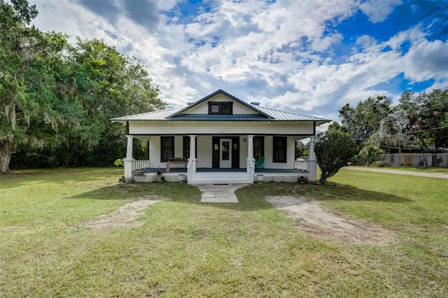 bungalow-style house featuring covered porch, metal roof, and a front lawn