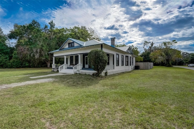 view of front of home with covered porch, metal roof, a chimney, and a front lawn