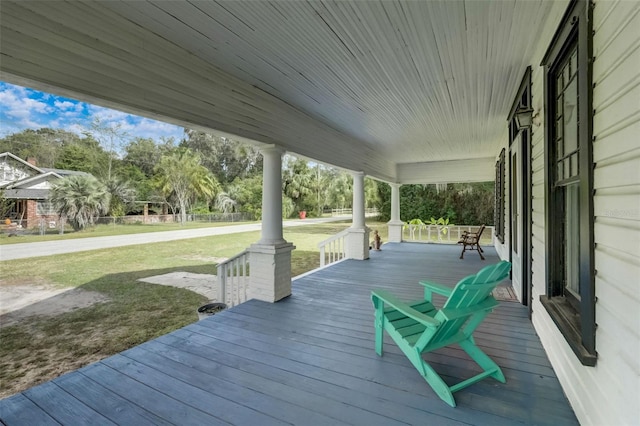 wooden deck featuring covered porch and a yard