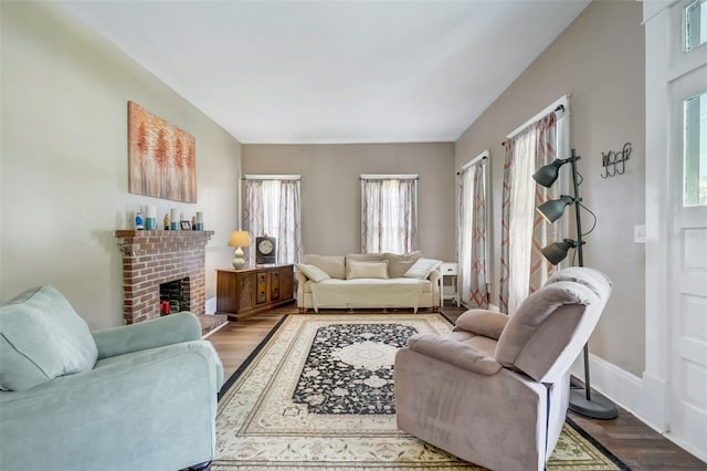 living room with a brick fireplace, wood finished floors, and baseboards