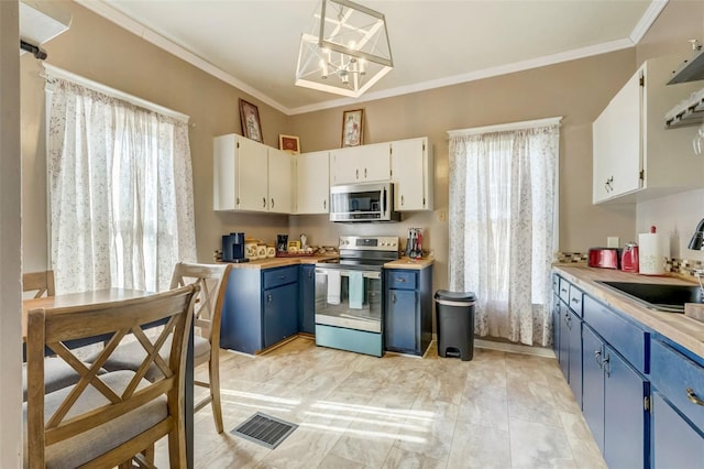 kitchen with visible vents, blue cabinets, stainless steel appliances, crown molding, and a sink