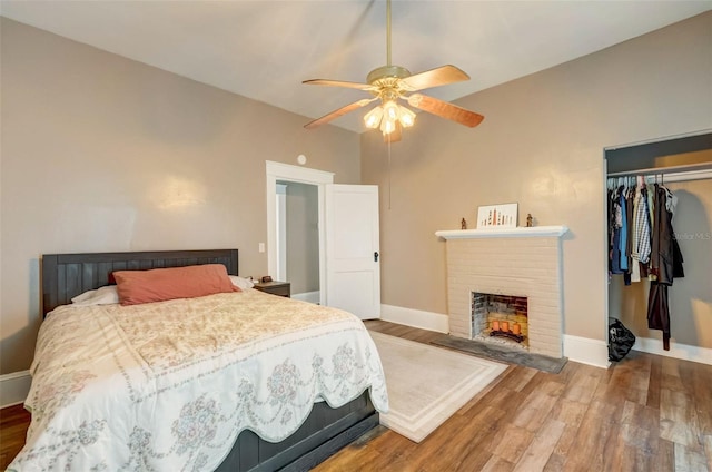 bedroom featuring a closet, a fireplace, wood finished floors, and baseboards