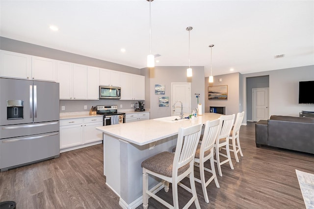 kitchen with white cabinets, dark wood finished floors, open floor plan, stainless steel appliances, and a sink