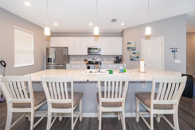 kitchen with appliances with stainless steel finishes, white cabinets, a sink, and a spacious island