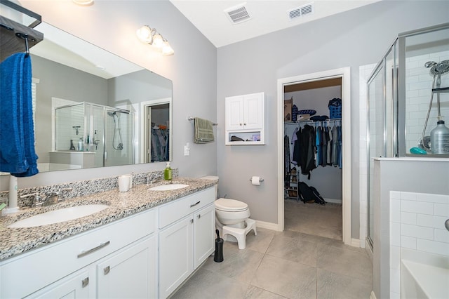 bathroom featuring a spacious closet, a stall shower, a sink, and visible vents