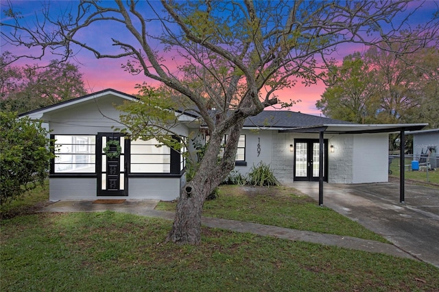 ranch-style house featuring a front yard, concrete block siding, and french doors