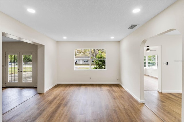 spare room featuring arched walkways, wood finished floors, visible vents, and recessed lighting