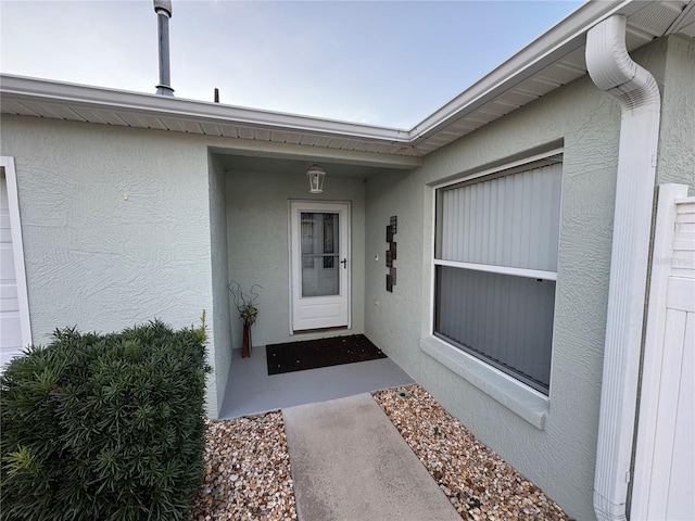 doorway to property featuring stucco siding