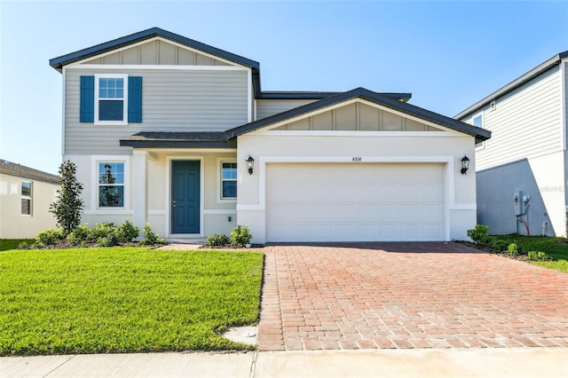 view of front of home with an attached garage, board and batten siding, a front yard, and decorative driveway