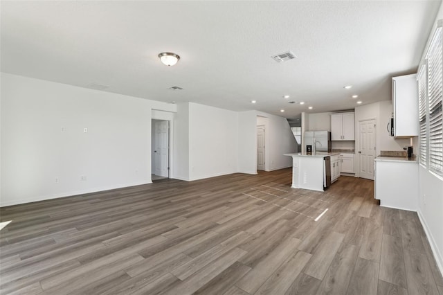 unfurnished living room featuring baseboards, light wood-style flooring, visible vents, and recessed lighting