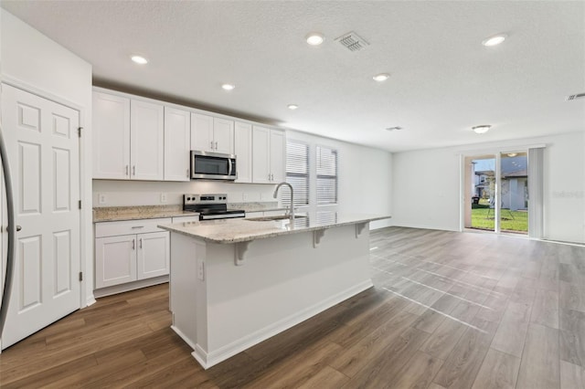 kitchen with plenty of natural light, appliances with stainless steel finishes, light stone counters, and visible vents