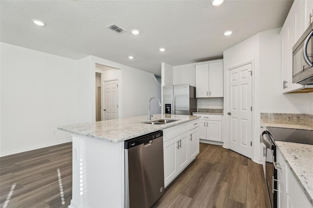 kitchen with an island with sink, a sink, stainless steel appliances, visible vents, and dark wood-style flooring