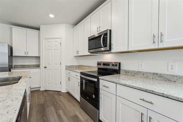 kitchen featuring dark wood-style flooring, light stone countertops, recessed lighting, appliances with stainless steel finishes, and white cabinetry