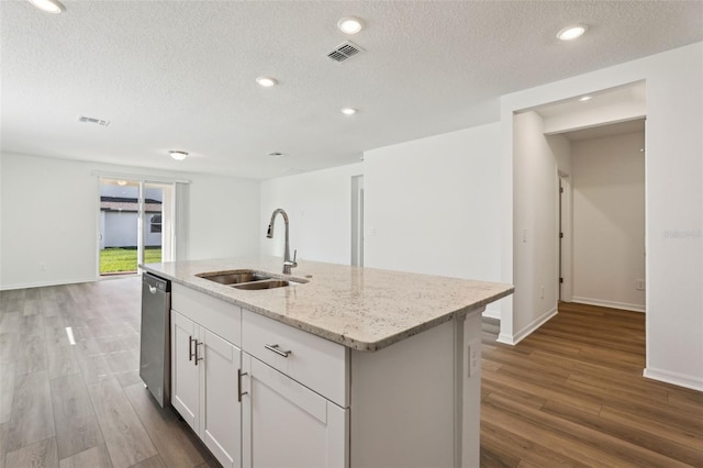 kitchen featuring dark wood-style flooring, a sink, visible vents, dishwasher, and light stone countertops