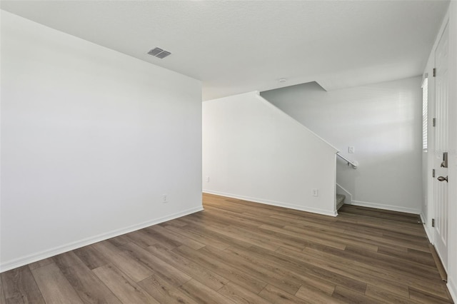 interior space featuring wood finished floors, baseboards, stairs, and visible vents