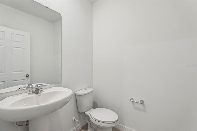 bathroom with toilet, a sink, and baseboards