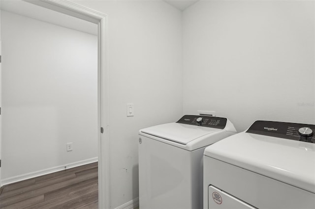 laundry area featuring baseboards, wood finished floors, laundry area, and washer and dryer