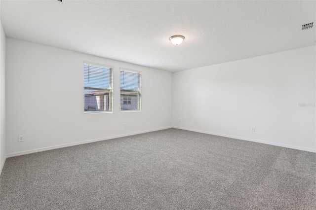 carpeted empty room featuring baseboards, visible vents, and a textured ceiling